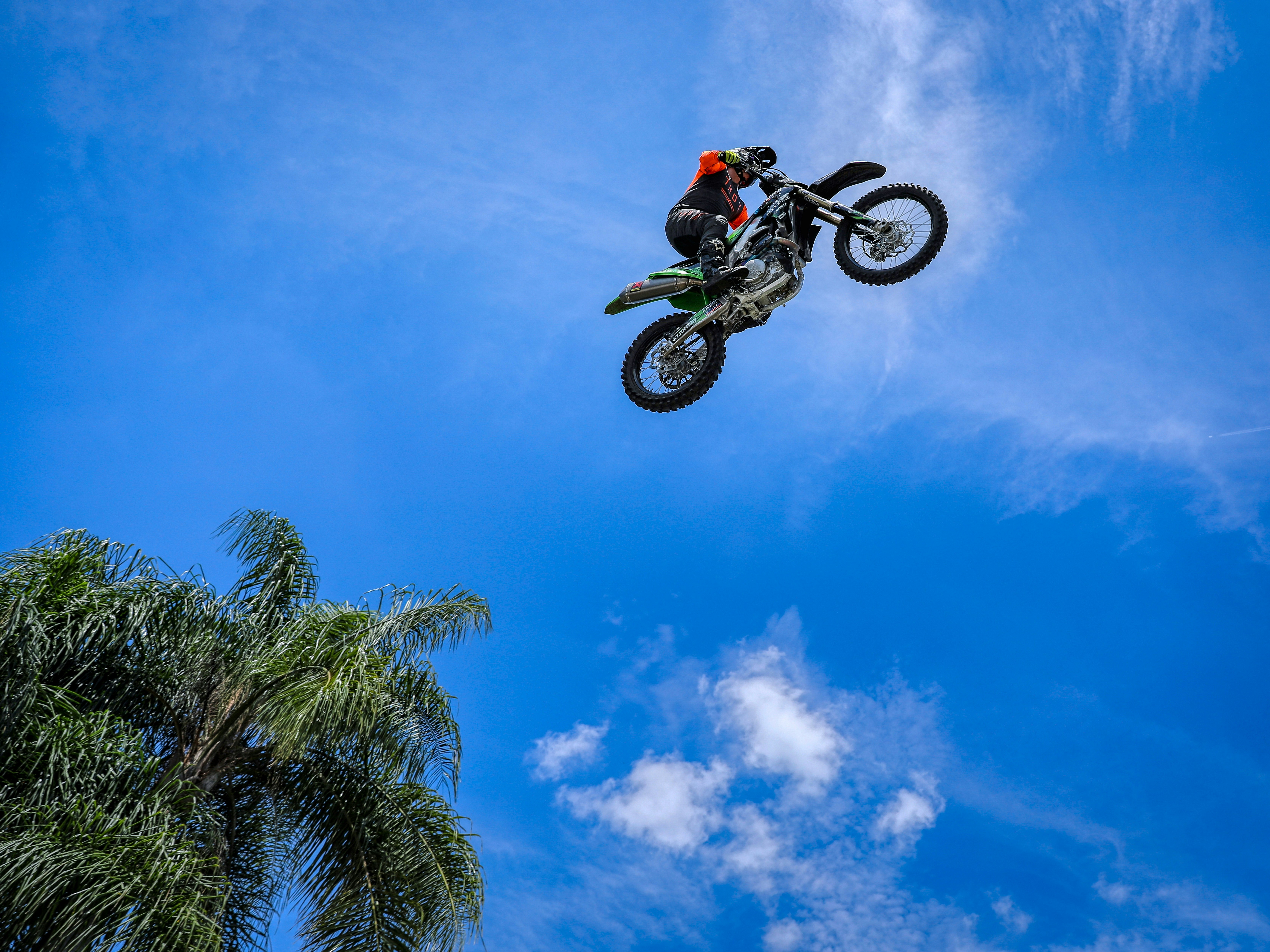 man riding motocross dirt bike under blue sky during daytime